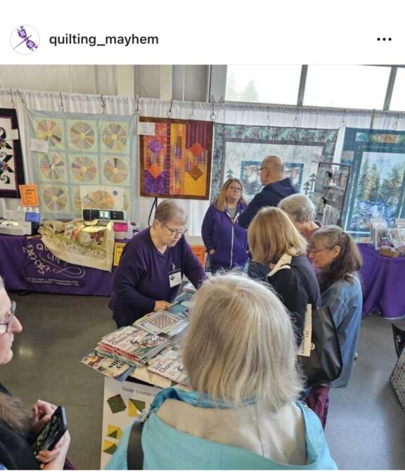 Quilters watch a demonstration at a quilt show booth