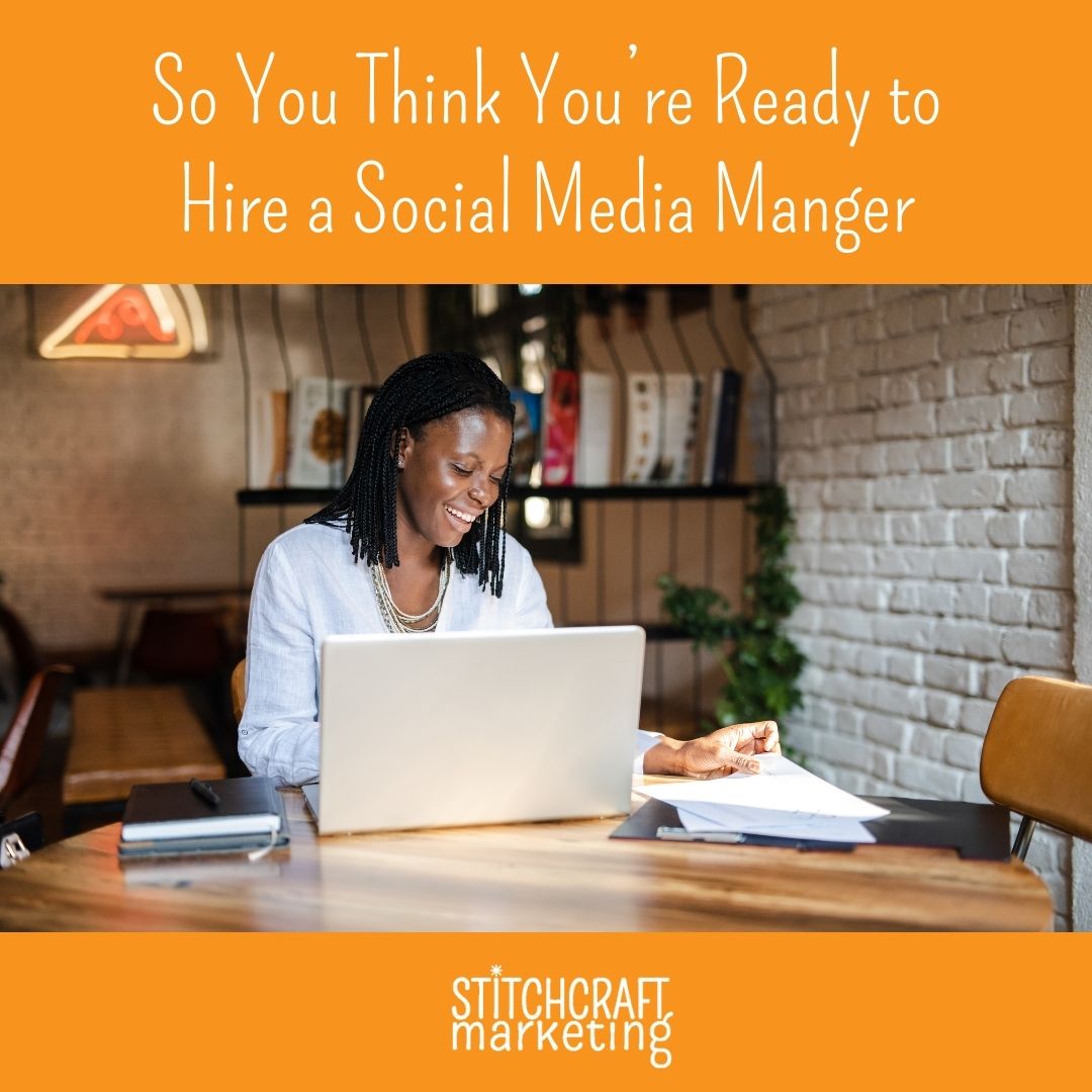 A woman sits at a table looking at a laptop and assorted pages. Text above reads "So You Think You're Ready to Hire a Social Media Manager"